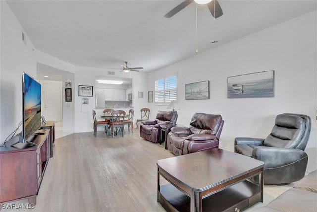 living area with light wood-style floors, visible vents, and ceiling fan