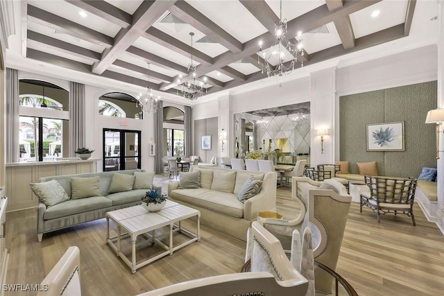 living area with a towering ceiling, plenty of natural light, a chandelier, and wood finished floors