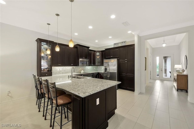 kitchen featuring stainless steel appliances, backsplash, glass insert cabinets, a sink, and a kitchen bar