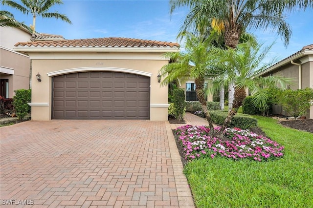 mediterranean / spanish-style home featuring a garage, decorative driveway, and stucco siding