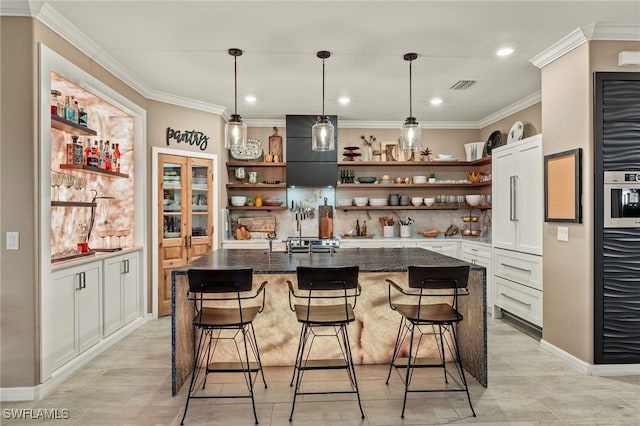 kitchen featuring white cabinets, a center island with sink, a kitchen bar, and open shelves