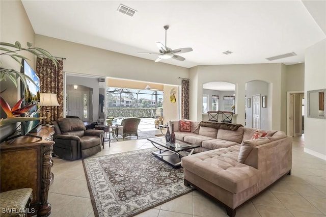 living area featuring arched walkways, visible vents, and light tile patterned floors