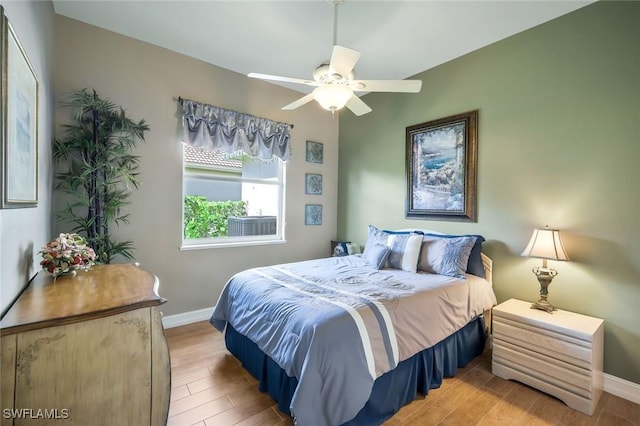 bedroom with light wood-style floors, baseboards, and a ceiling fan