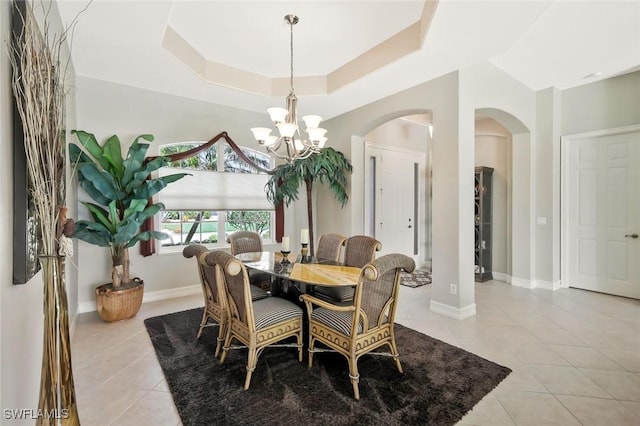 dining space with baseboards, a tray ceiling, a chandelier, and light tile patterned flooring