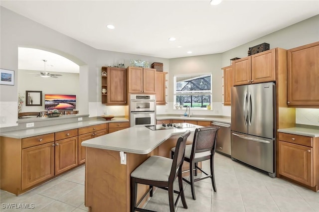 kitchen with a kitchen island, a breakfast bar, stainless steel appliances, light countertops, and open shelves