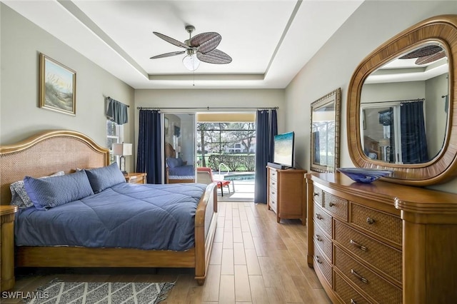 bedroom featuring a ceiling fan, a raised ceiling, and wood finished floors