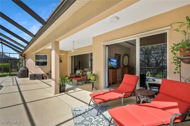 view of patio / terrace featuring ceiling fan, glass enclosure, and an outdoor living space