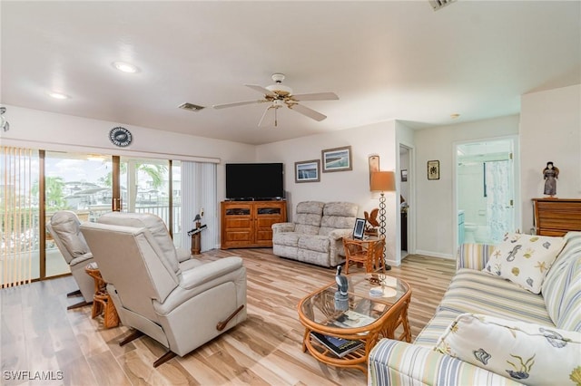 living room with a ceiling fan, visible vents, light wood-style flooring, and baseboards