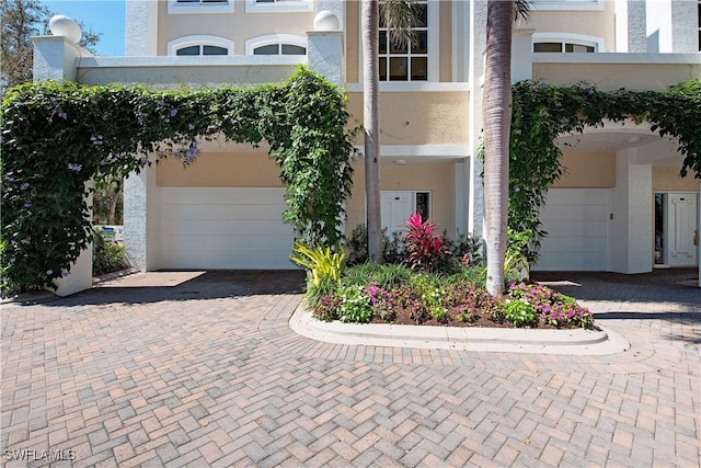 view of front facade featuring a garage, decorative driveway, and stucco siding