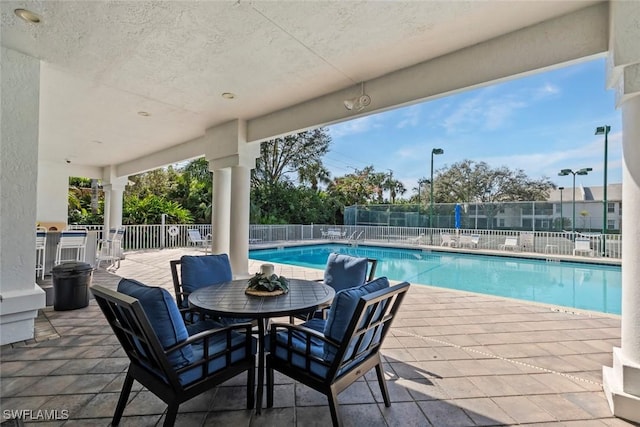 pool with a patio area and fence