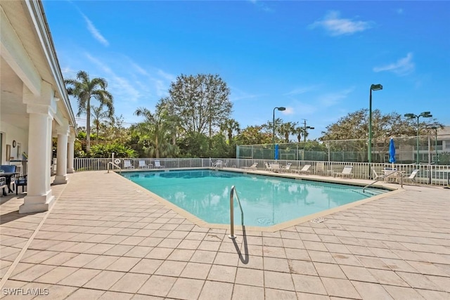 community pool with a patio and fence