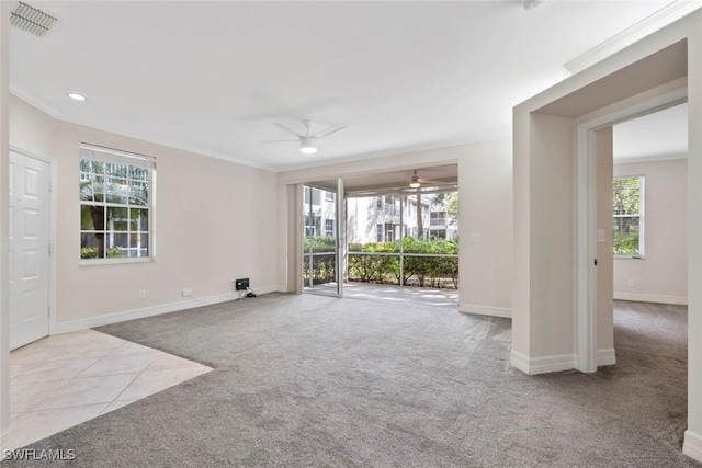 carpeted spare room with ornamental molding, tile patterned flooring, a wealth of natural light, and baseboards