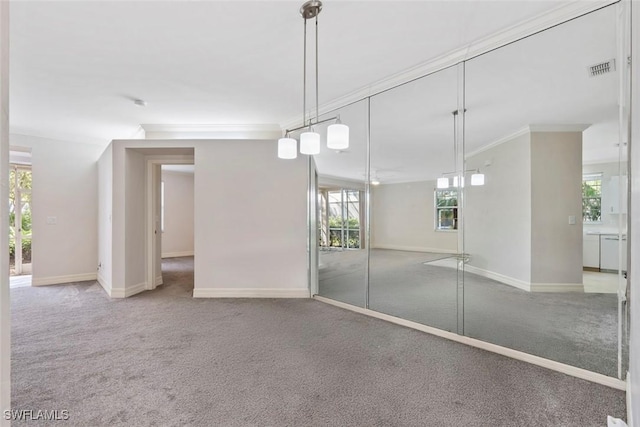 empty room with ornamental molding, carpet, visible vents, and baseboards