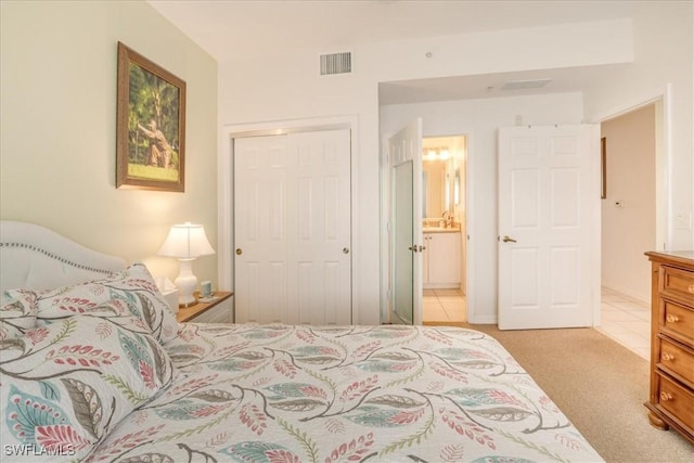 carpeted bedroom featuring ensuite bathroom, a closet, and visible vents