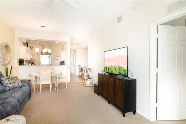 living room with light carpet, visible vents, and ceiling fan with notable chandelier