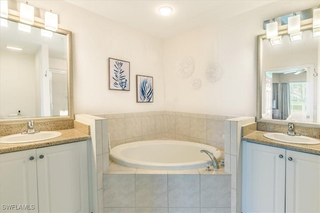 full bathroom featuring two vanities, a garden tub, and a sink