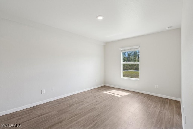 unfurnished room with baseboards and wood finished floors