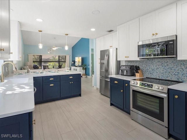 kitchen with blue cabinets, appliances with stainless steel finishes, light countertops, and pendant lighting