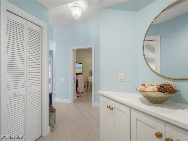 bathroom with baseboards, wood finished floors, a closet, and vanity