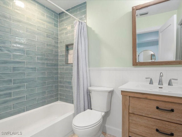 bathroom with wainscoting, shower / bathtub combination with curtain, toilet, and vanity