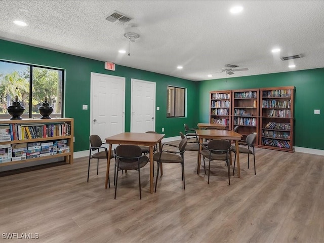 dining area featuring visible vents, wood finished floors, a ceiling fan, and baseboards