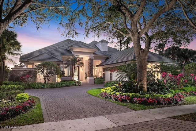 view of front of property with decorative driveway, a tile roof, and stucco siding