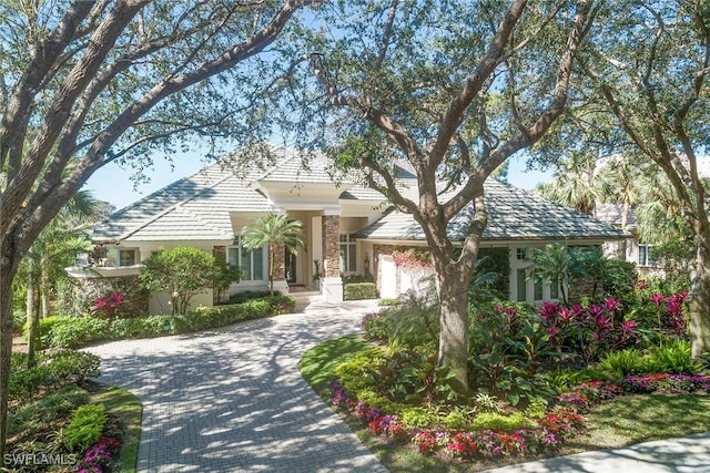 view of front of house with a garage, stone siding, and decorative driveway