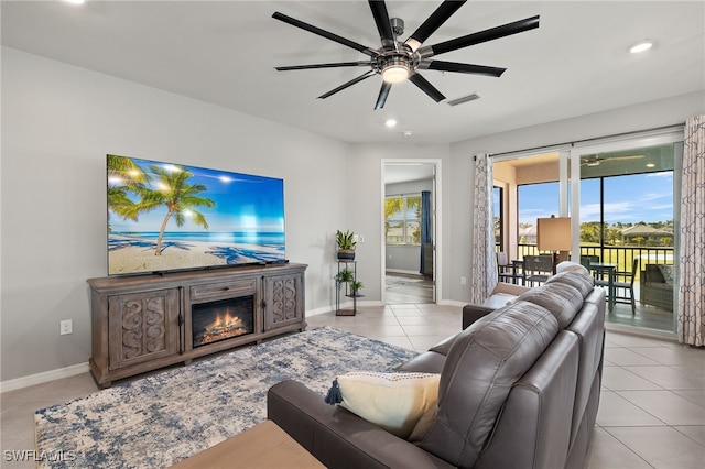 living area with a wealth of natural light, baseboards, ceiling fan, and light tile patterned flooring