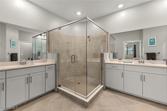 bathroom featuring a sink, two vanities, a stall shower, and tile patterned flooring