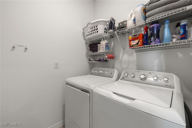 clothes washing area featuring washer and clothes dryer, laundry area, and baseboards