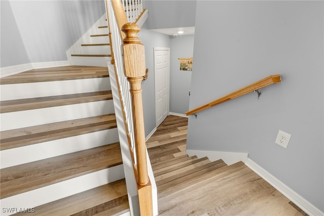 staircase with baseboards and wood finished floors