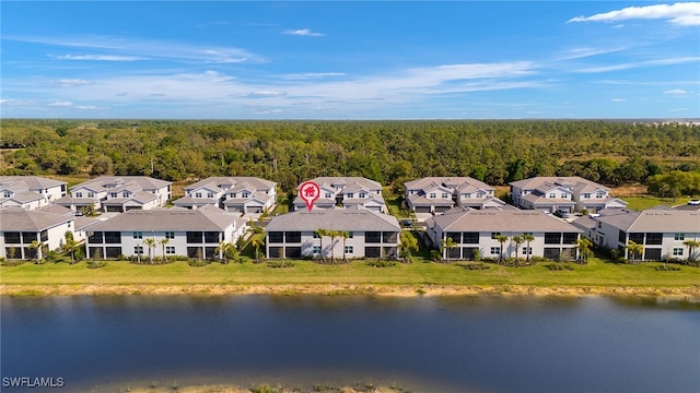 drone / aerial view with a forest view, a residential view, and a water view