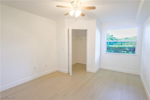 unfurnished bedroom featuring light wood-style floors, a textured ceiling, and baseboards