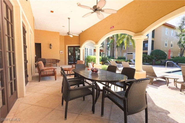 view of patio featuring outdoor dining space, a community pool, a ceiling fan, and french doors