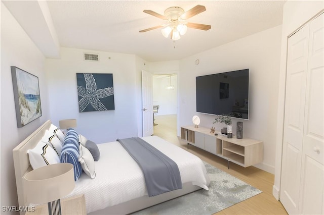 bedroom with light wood-style flooring, visible vents, ceiling fan, and a closet