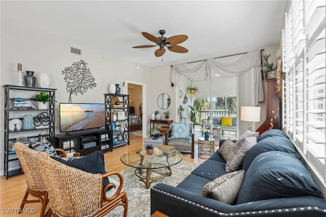 living room featuring light wood-type flooring, visible vents, and ceiling fan