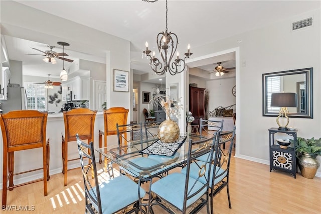 dining room with a notable chandelier, baseboards, visible vents, and light wood finished floors