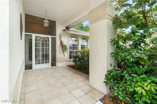 property entrance with a patio, roof with shingles, and stucco siding