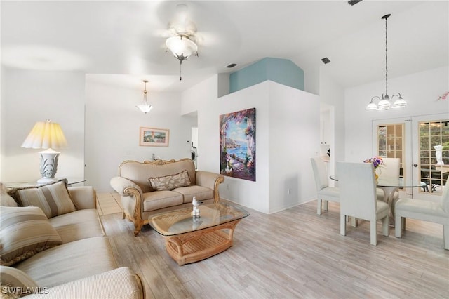 living area featuring a chandelier, high vaulted ceiling, light wood finished floors, and visible vents