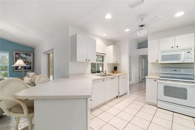 kitchen featuring a peninsula, white appliances, a sink, visible vents, and light countertops