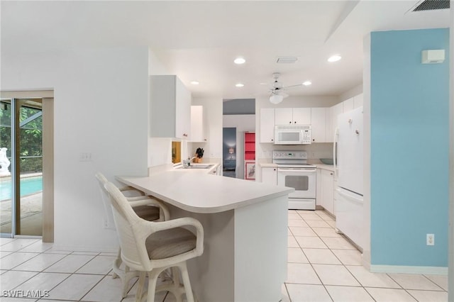 kitchen featuring light tile patterned floors, visible vents, a sink, white appliances, and a peninsula