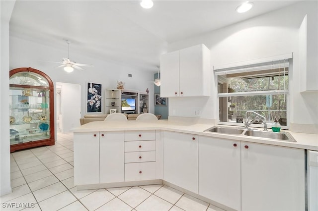 kitchen with light countertops, open floor plan, white cabinetry, a sink, and a peninsula