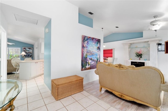 living room with visible vents, vaulted ceiling, a fireplace, and light tile patterned flooring