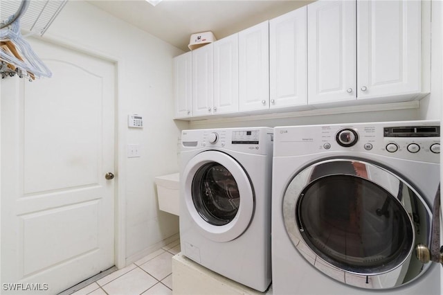 laundry room with light tile patterned floors, separate washer and dryer, and cabinet space