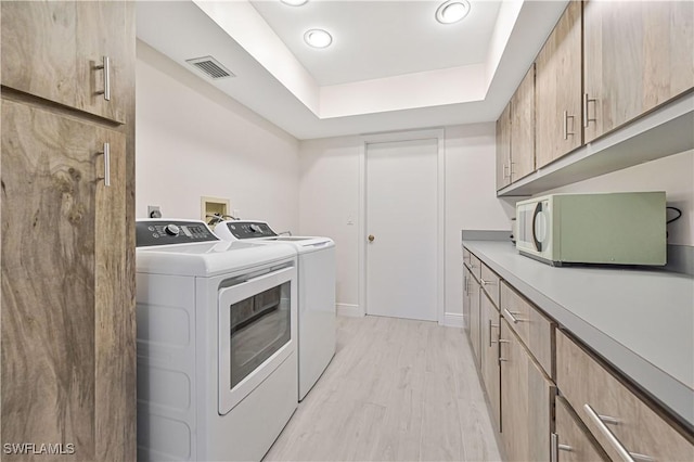 laundry area with light wood finished floors, visible vents, and washing machine and clothes dryer