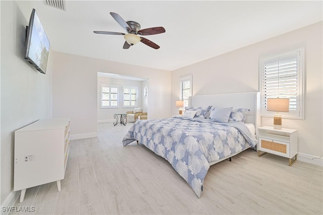 bedroom featuring baseboards, a ceiling fan, visible vents, and light wood-style floors