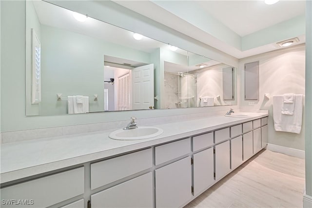 full bath with double vanity, visible vents, a sink, and wood finished floors