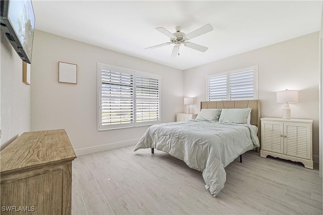 bedroom with ceiling fan, light wood-style flooring, and baseboards