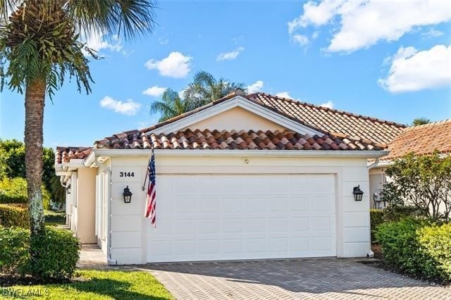 view of front of house with driveway, a tiled roof, an attached garage, and stucco siding