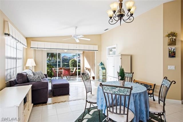 dining room with light tile patterned floors, baseboards, vaulted ceiling, and ceiling fan with notable chandelier